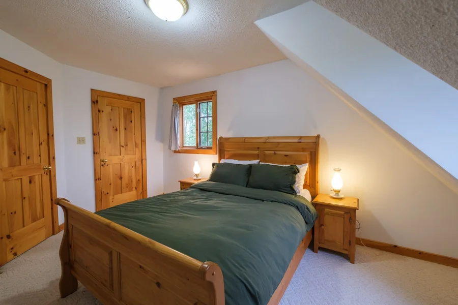 Upstairs queen bedroom with wooden bed frame and green bedding